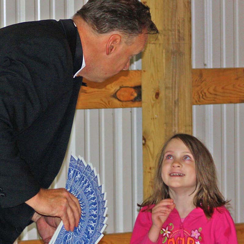 a young girl smiling at a man holding a fan